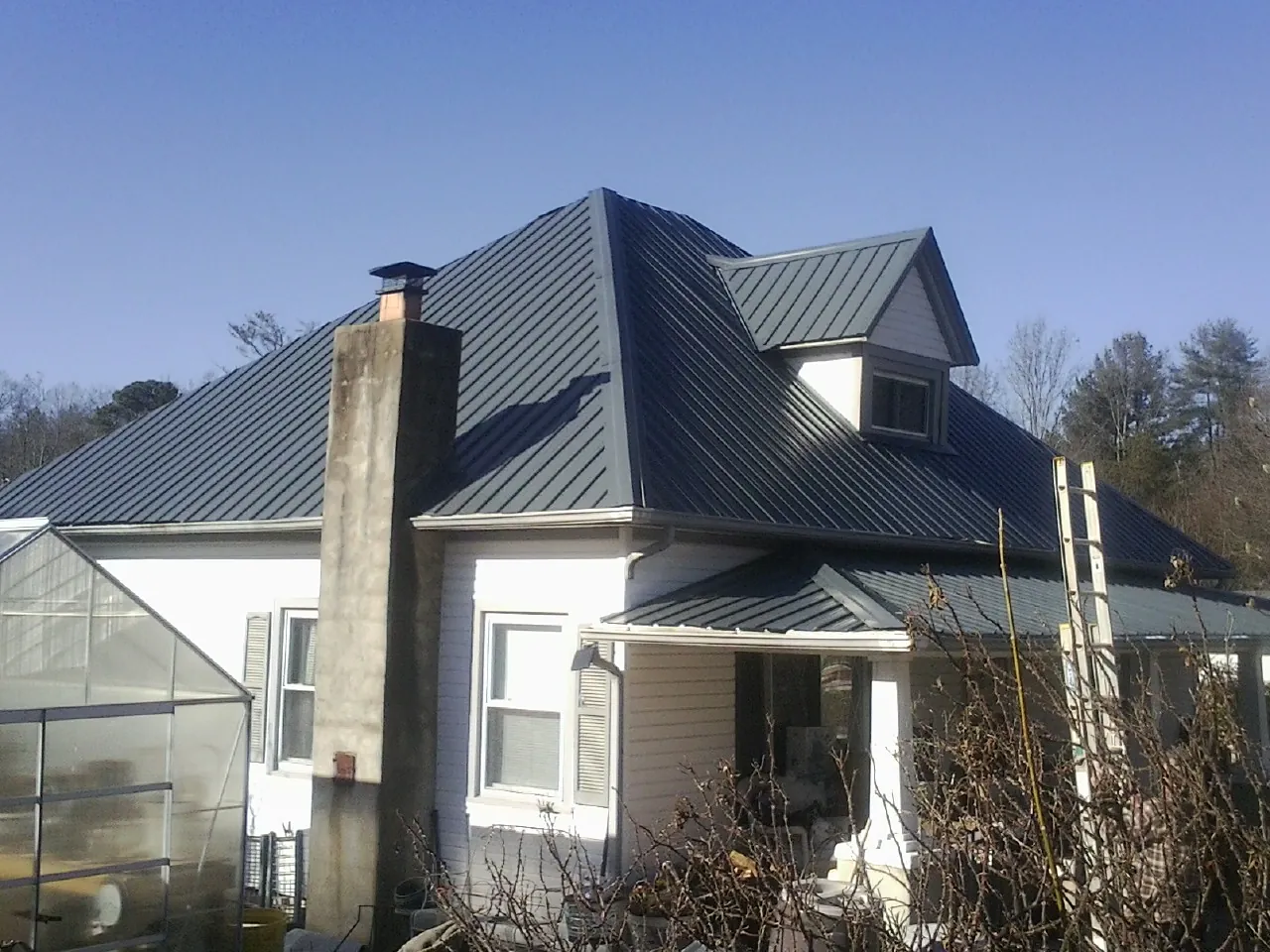 Dark blue standing seam metal roof on a white farmhouse with dormer — Slate & Tile Roof Repair by Roofing Brothers in Stoneboro
