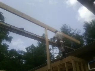 Carpenter setting a ridge beam over a new addition frame — Ice Dam Removal by Roofing Brothers in Stoneboro