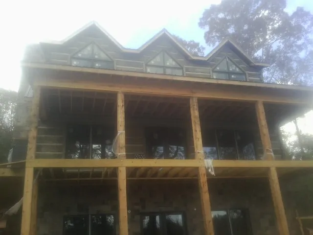 Dormers and porch framing on a large log home under construction — Roof Coating work by our crew in Stoneboro