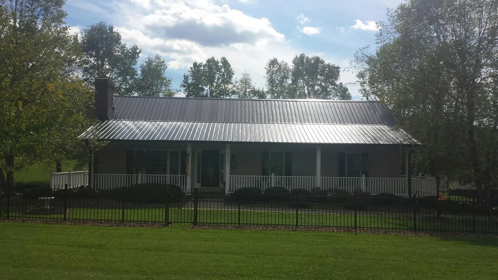 Gray metal roof on a brick ranch with a full width front porch — Gutter Guard Installation work by our crew in Stoneboro