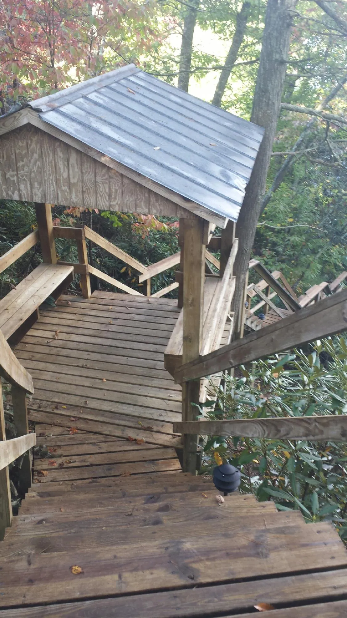 Metal roofed shelter over wooden steps on a wooded walkway — Skylight Repair & Installation work by our crew in Stoneboro