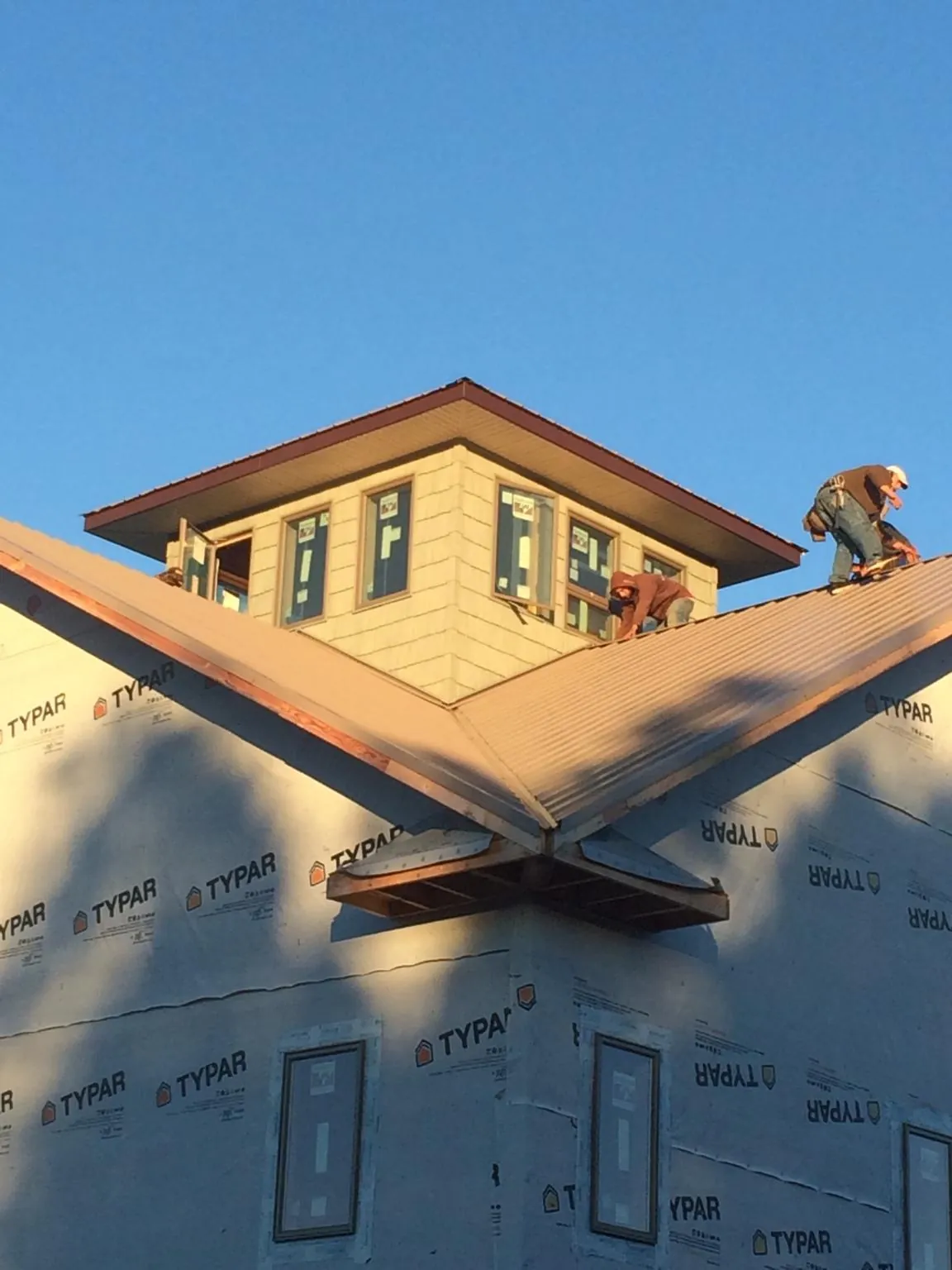 Roofers working around a rooftop cupola on a new metal roof at sunset — Roof Waterproofing in Stoneboro by Roofing Brothers